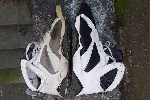 Pair of worn and dirty white and black athletic sneakers placed side by side on concrete steps.